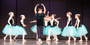 A young boy doing ballet with a group of girls