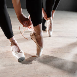 Two dancers tighten their shoes