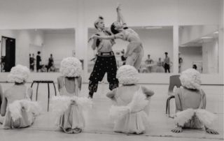 Historical dance costumes with young dancers watching two professionals all of them in elaborate costume