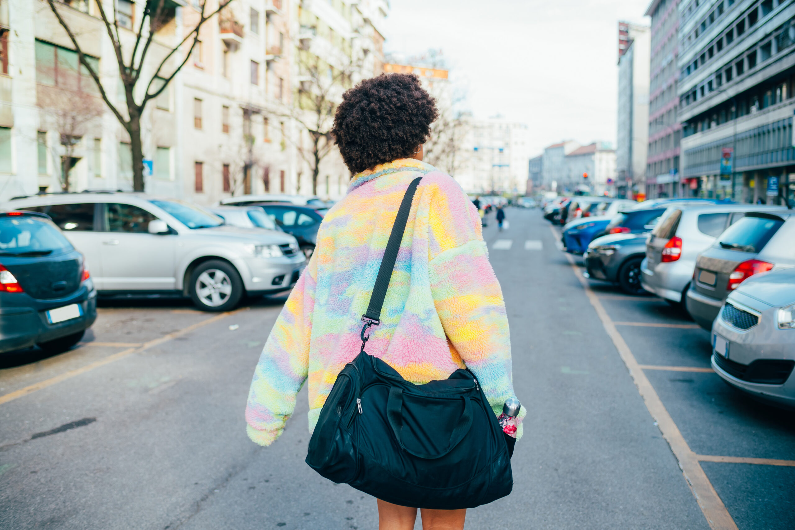 Back view young woman walking outdoor city with duffle bag going gym