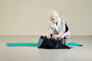 Professional female dancer taking towel and speaker out of dance bag in class